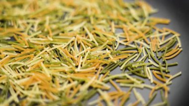 İtalyan usulü, pişmemiş vermicelli siyah seramik tabak. Organik kuru besin maddesi. Makro atış. Döndürme