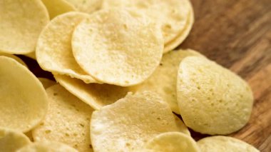 Tahta desenli altın patates cipsi yakından. Sağlıksız yüksek kalorili atıştırmalıklar. Döndürme