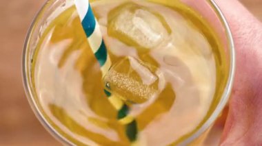 Elin bir bardak soğuk yeşil çay tutuyor. Buz küpleriyle organik içecek ve pipet içmek.