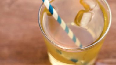 Eski limonata bardakta el ele tutuşup kamış ve buz parçalarını ahşap masanın üzerinde içiyorlar.