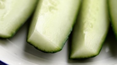 Yakın plan kesilmiş salatalıklı beyaz seramik tabak. Besleyici sebze yemeği. Döndürme. Ön görünüm.