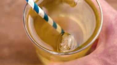 Soğuk limonata, şeffaf bardakta buzlu yeşil çay ve ahşap bar masasında pipet içmek.