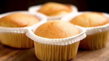 Tahta masadaki kağıt bardaklarda taze pişmiş vanilyalı kek grubu. Döndürme