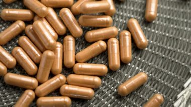 Bitkisel kapsülleri tıbbî özü yeşil hasır dokusuna yavaşça düşen kapsüllerle kaplayın. Alternatif ilaç hapları