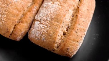 İnsan eliyle alınan siyah tabakta pişmiş ekmek ekmeği. Kıtır kıtır kıtır ve chia tohumlu. Fırın ürünü