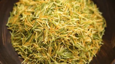 Çok renkli, ince İtalyan vermicelli ağır çekimde ahşap kahverengi kaseye düşüyor. Üst Manzara. Pişmemiş organik geleneksel malzeme