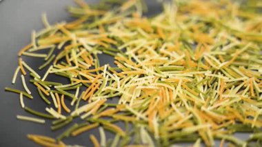 Siyah seramik yüzeyine düşen renkli vermicelli makarna. İtalyan geleneksel kuru malzemesi. Makro atış. Yavaş çekim