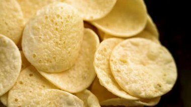 Siyah bir kasede tuzlu patates cipsi. Çıtır çıtır fast food. Üst Manzara. Döndürme