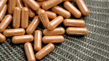 Kahverengi tıbbi vitamin kapsülleri doğal hasır üzerinde. Döndürme