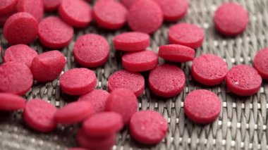 B12 ilave haplar, dokulu bir hasır yüzeyde. Kırmızı vitamin metilkobalamin hapları. Döndürme