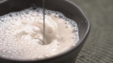 Elektrikli köpük, bitki bazlı badem sütü smoothie 'yi yavaş çekimde karıştırıyor