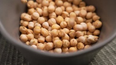 Pişmemiş bezelyeler yavaş çekimde gri bir mutfak kasesine düşüyorlar. Protein mutfak malzemesi.