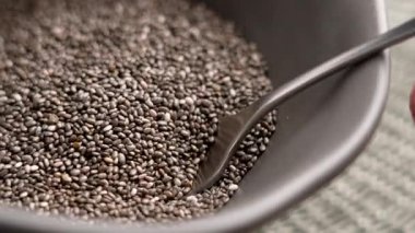 Metal kaşık gri kaseden çiğ diyet chia tohumları toplar. Makro çekim