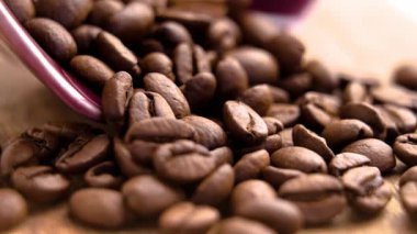 Kırmızı seramik kaseden yayılmış kavrulmuş Arap kahve çekirdekleri. Sabah içeceği. Döndürme