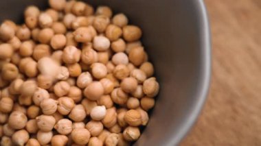 Kurumuş nohutlar ağır çekimde gri bir kaseye düşüyor. Pişmemiş garbanzo fasulyesi malzemesi. Üst görünüm