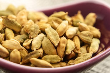 Kurutulmuş kakule kapsülleriyle dolu seramik bir kase. Geleneksel Hint baharatı. Makro. 