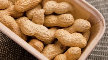 Hasır bir hasırın üzerinde, kağıt paketinin içinde kavrulmuş fıstık. Döndürme