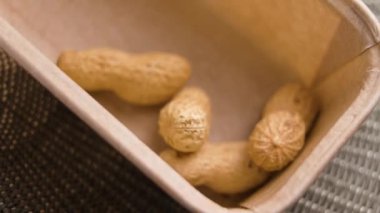 Kabuksuz kavrulmuş fıstık kağıt bir paketin içine düşüyor. Organik fındık. Makro atış. Yavaş çekim