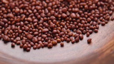 Kakao ve kakule karışımlı küçük granüller yavaş çekimde kırsal ahşap bir kaseye dökülüyor. Döndürme