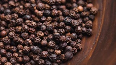 Kırsal ahşap bir kaseye dökülen karabiberli Aromatik biber. Ağır çekim. Döndürme