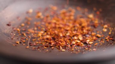 Ezilmiş kırmızı kırmızıbiber çeşnisi ağır çekimde ahşap kaseye dökülüyor.