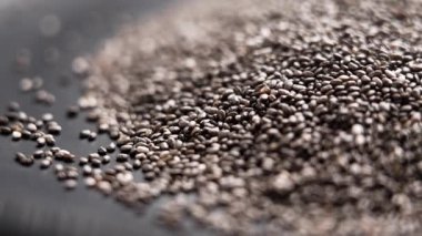 Siyah seramik tabakta kurumuş sağlıklı chia tohumları yığını. Makro. Döndürme