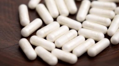 Tahta kasede beyaz B-1 vitamini takviye kapsülü yığını. Makro. Döndürme