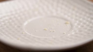 Badem fıstıklı un taneleri yavaş çekimde seramik tabağa düşüyor. Makro çekim