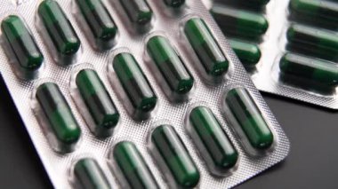 Yeni açılmamış folyo paketleri yeşil bitkisel kapsüller ve bir paket ilave hap.