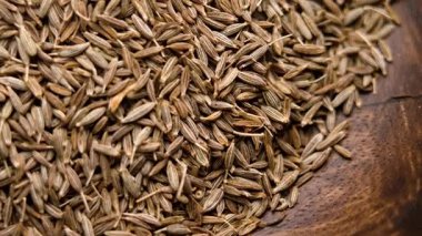 Kahverengi ahşap dokuda kurutulmuş kimyon tohumları. Aromatik baharat. Organik malzeme. Üst Manzara. Makro atış. Döndürme