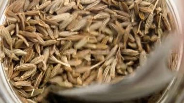 Metal kaşık kepçeleri cam kavanozdan kurutulmuş kimyon tohumları. Aromatik baharat. Organik malzeme. Üst Manzara. Makro çekim