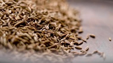 Aromatik kimyon tohumları ahşap kırsal kaseye düşüyor. Organik Asya baharatı. Makro. Yavaş çekim