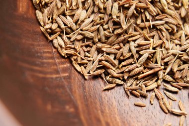Kahverengi ahşap dokuda kurutulmuş kimyon tohumları. Aromatik baharat. Organik malzeme. Üst Manzara. Makro çekim. 