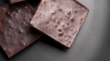 Siyah seramik tabakta çilekli kırık çikolataların kareleri. Döndürme