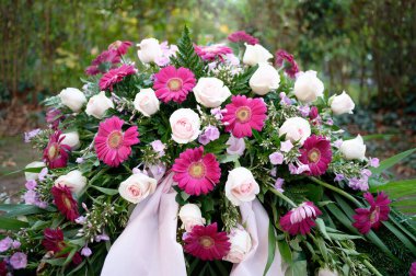 Mor ve pembe güller ve mezardaki cenaze çiçekleri gibi gerbera
