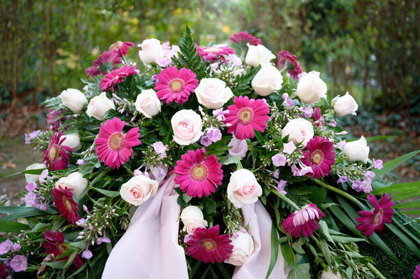 purple and pink roses and gerbera as funeral flowers on a grave