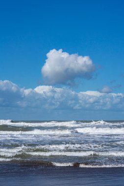 Sahile yakın dalgalar, ufukta fırtına ve bulutlar.