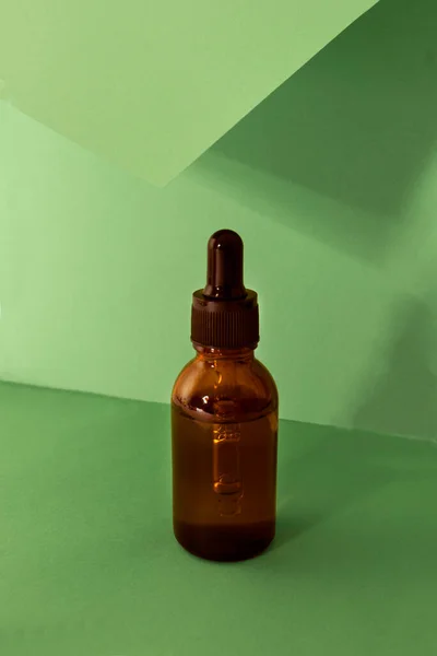 Glass cosmetic bottles with a dropper on a green background. The concept of natural cosmetics, natural essential oil