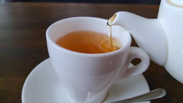 お茶は白いティーポットから白いカップに注ぎます スロービデオ — ストック動画