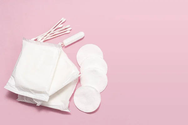 The concept of feminine hygiene, tampons, pads on a pink background