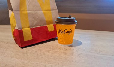 Vinnitsya, Ukrayna... 21 Mart 2025 McDonalds markalı kahve bardağı ve McDonalds 'ın kafesindeki bir masanın üzerinde bir poşet var.