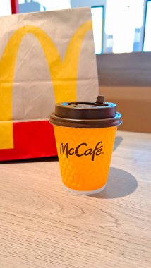Vinnitsya, Ukrayna... 21 Mart 2025 McDonalds markalı kahve bardağı ve McDonalds 'ın kafesindeki bir masanın üzerinde bir poşet var.