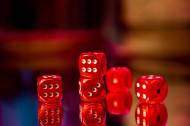 Masanın ayna yüzeyinde kırmızı zarlar var..