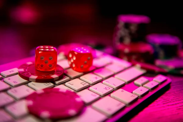 Online casino. Online poker. On the table there are game pieces and dice next to the keyboard. Game chips for betting in gambling. Dice. Poker chips.