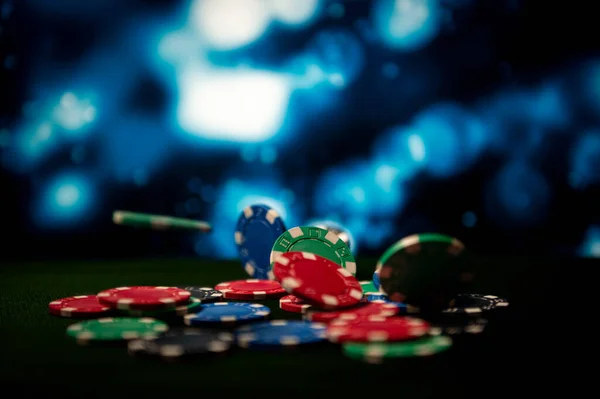 Casino. Game chips fall on the table against a blurred dramatic background. Poker chips in motion. Game chips for betting in gambling. Poker chips.