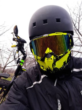 A cyclist in a helmet and mask in front of a fatbike after a trip around the city.