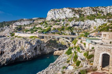 Agosto 17, 2022 - The Ciolo bridge, Gagliano del Capo. An inlet of the sea. The panorama of the splendid coast of Salento, in Puglia. The rocky cliff and the restaurants overlooking the sea. clipart