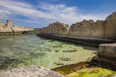 Marina Serra 'nın inanılmaz doğal havuzları, Puglia, Salento, Tricase' de. Kayalık uçurumun arasındaki berrak ve kristal turkuaz deniz. Yazın mavi gökyüzü. Eski gözetleme kulesi..