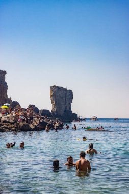 15 Ağustos 2023 - Santa Cesarea Terme, Salento, Puglia, İtalya. Porto Miggiano 'nun inanılmaz körfezi. Turistlerle, banyolarla ve teknelerle dolu, harika denizin tadını çıkarıyorlar, berrak, mavi ve turkuaz..