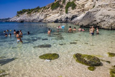 15 Ağustos 2023 - Santa Cesarea Terme, Salento, Puglia, İtalya. Porto Miggiano 'nun inanılmaz körfezi. Turistlerle, banyolarla ve teknelerle dolu, harika denizin tadını çıkarıyorlar, berrak, mavi ve turkuaz..